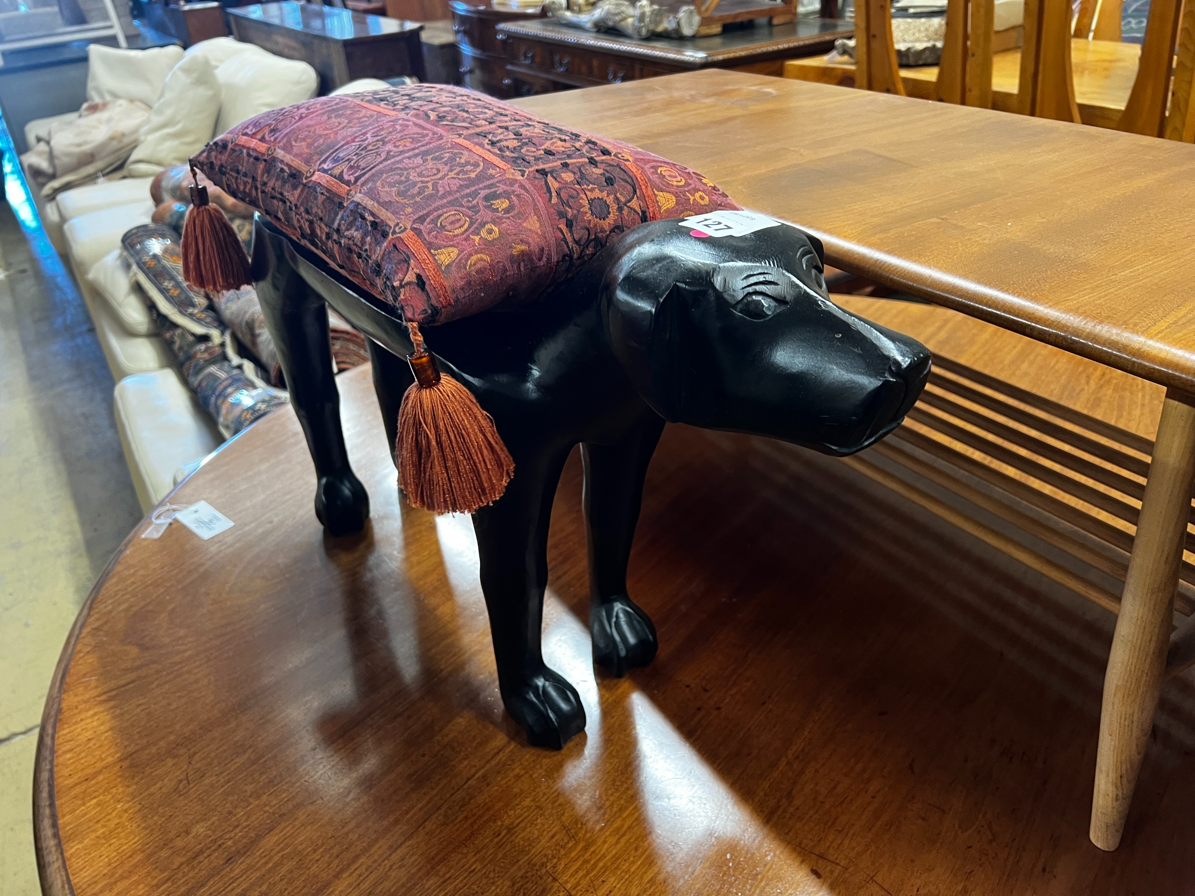 A carved hardwood 'dog' foot stool, with cushion, length 66cm